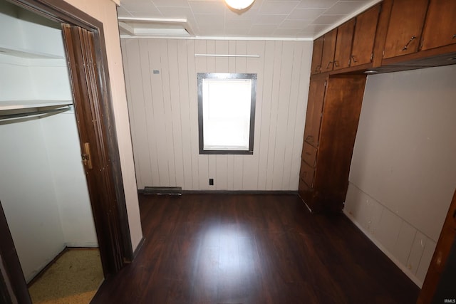 unfurnished bedroom featuring dark wood-type flooring and wood walls