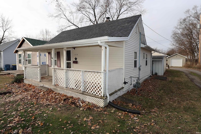 view of property exterior featuring a garage, covered porch, and an outbuilding