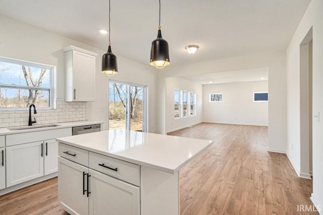 kitchen featuring white cabinetry, decorative backsplash, decorative light fixtures, a kitchen island, and sink