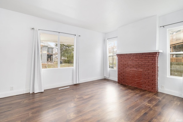 empty room with dark hardwood / wood-style flooring and a fireplace