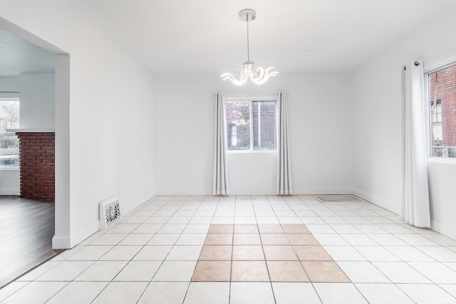 spare room featuring light tile patterned floors and a chandelier