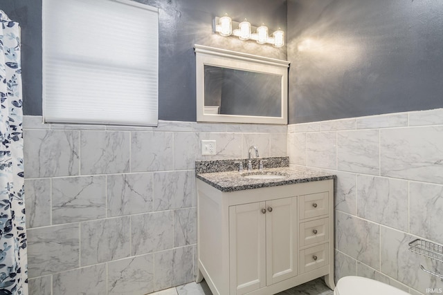 bathroom with vanity, toilet, and tile walls