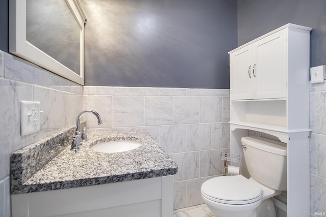 bathroom featuring vanity, toilet, and tile walls