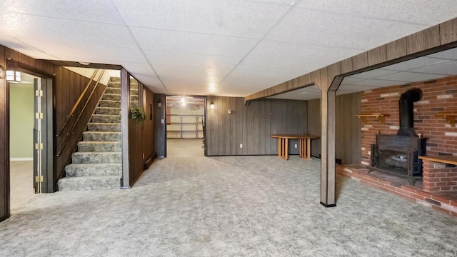 basement with wooden walls, a drop ceiling, and carpet floors