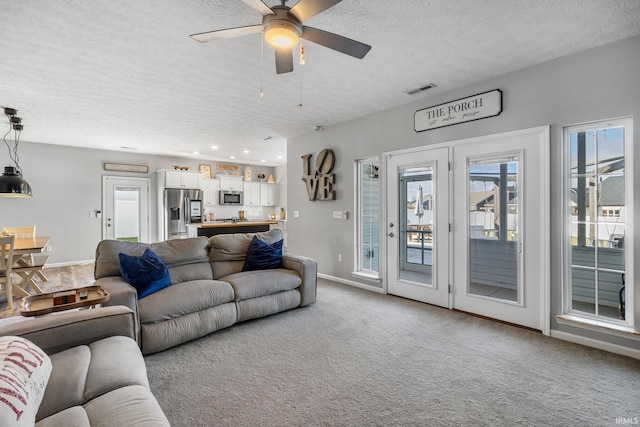 living room featuring ceiling fan, carpet, and a textured ceiling