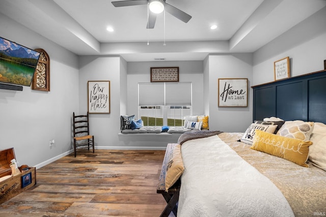 bedroom featuring dark hardwood / wood-style flooring, a tray ceiling, and ceiling fan