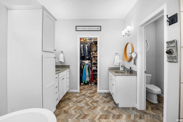 bathroom with vanity, a bathtub, parquet floors, and toilet