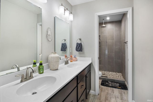 bathroom featuring tiled shower, toilet, vanity, and hardwood / wood-style flooring