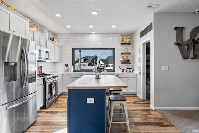 kitchen featuring a kitchen bar, appliances with stainless steel finishes, white cabinetry, and a kitchen island