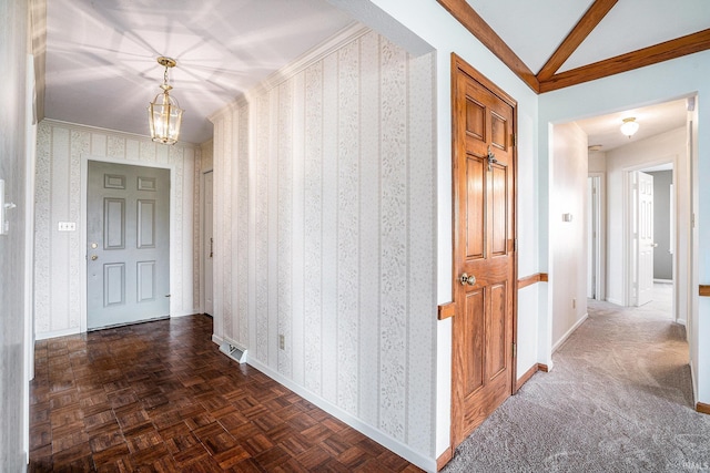 corridor with lofted ceiling, dark parquet floors, ornamental molding, and a notable chandelier