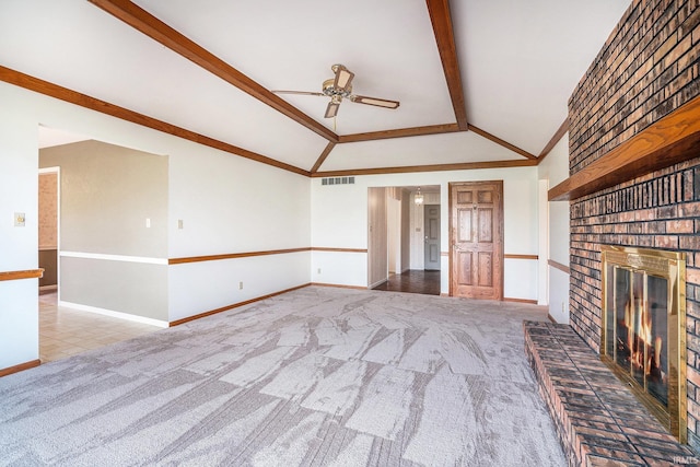 unfurnished living room featuring ceiling fan, lofted ceiling with beams, crown molding, light colored carpet, and a fireplace