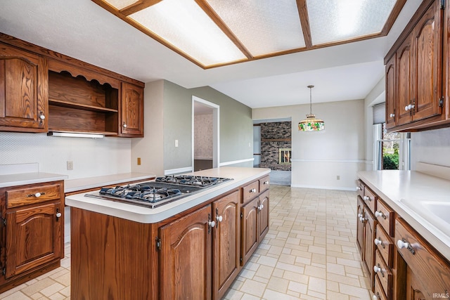 kitchen with hanging light fixtures, a center island, stainless steel gas stovetop, and a fireplace