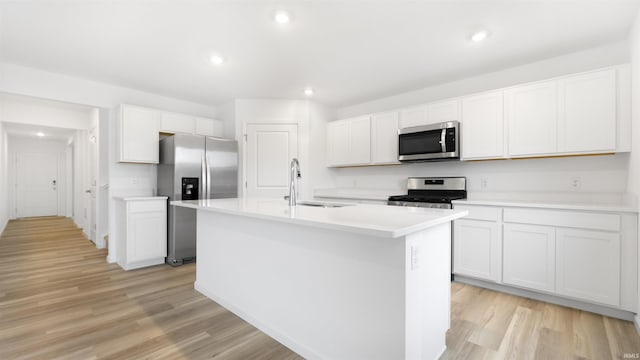 kitchen featuring a kitchen island with sink, white cabinets, sink, light wood-type flooring, and appliances with stainless steel finishes