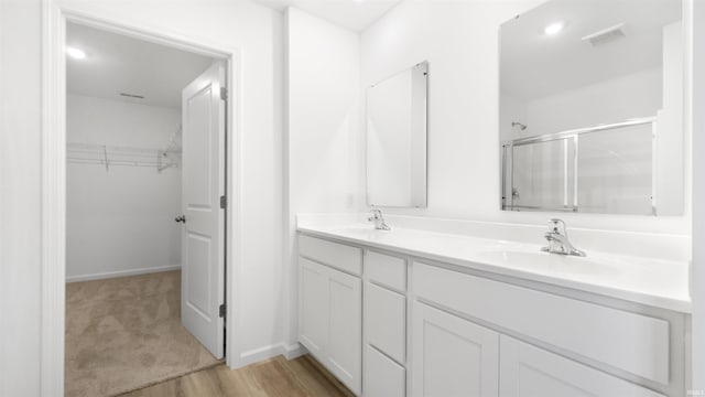 bathroom with wood-type flooring, vanity, and walk in shower