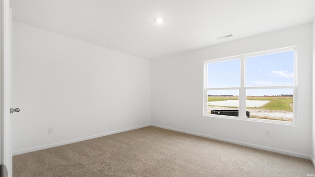 carpeted spare room with a water view