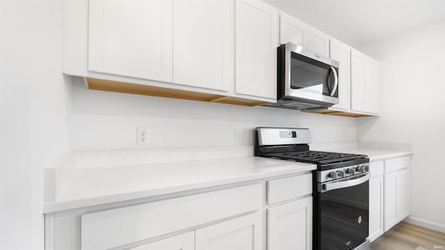 kitchen featuring stainless steel appliances, white cabinetry, and light hardwood / wood-style flooring