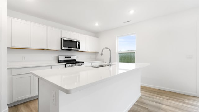 kitchen with white cabinets, sink, an island with sink, and white gas range oven