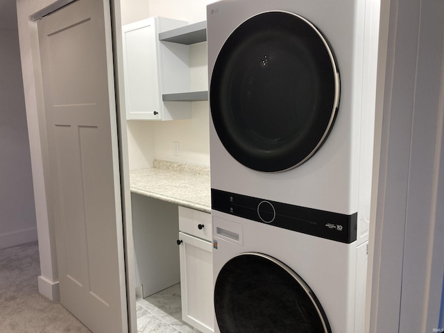 washroom with stacked washer / dryer and cabinets