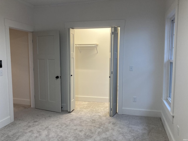 unfurnished bedroom featuring light colored carpet, a spacious closet, and a closet