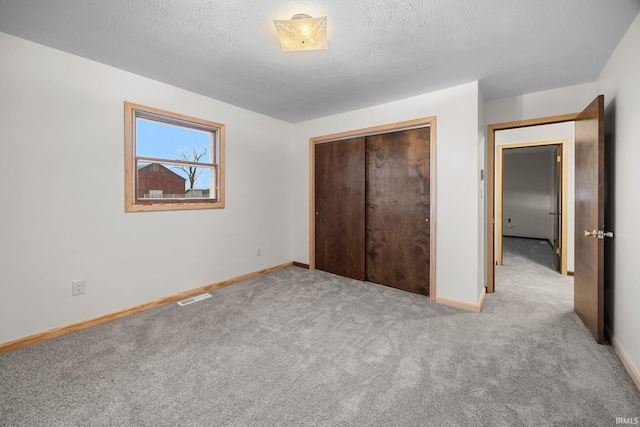 unfurnished bedroom with a textured ceiling, light colored carpet, and a closet