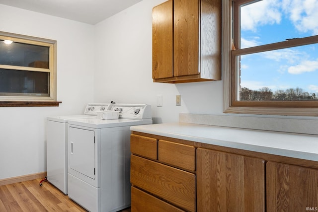 laundry room with separate washer and dryer, light hardwood / wood-style flooring, and cabinets