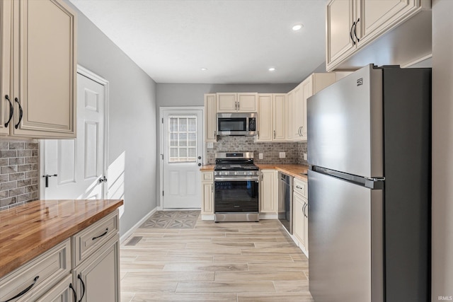 kitchen with backsplash, light hardwood / wood-style floors, stainless steel appliances, and wood counters