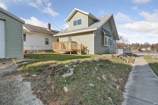 back of house with a deck and a lawn