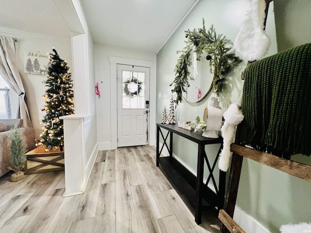 foyer entrance with light wood-type flooring and ornamental molding