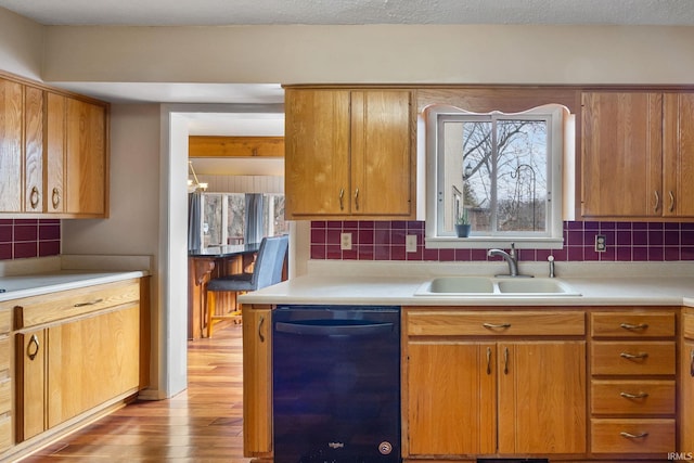 kitchen featuring tasteful backsplash, sink, light wood-type flooring, and black dishwasher