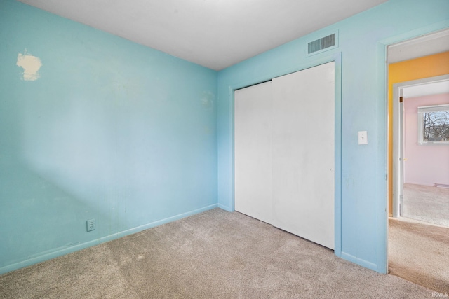 unfurnished bedroom featuring light colored carpet and a closet