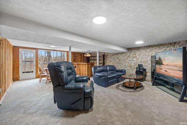 living room with carpet, wood walls, and a textured ceiling