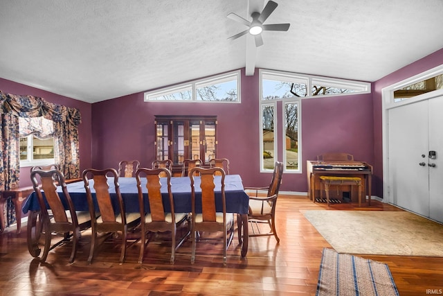 dining room featuring hardwood / wood-style floors, vaulted ceiling with beams, ceiling fan, and a textured ceiling