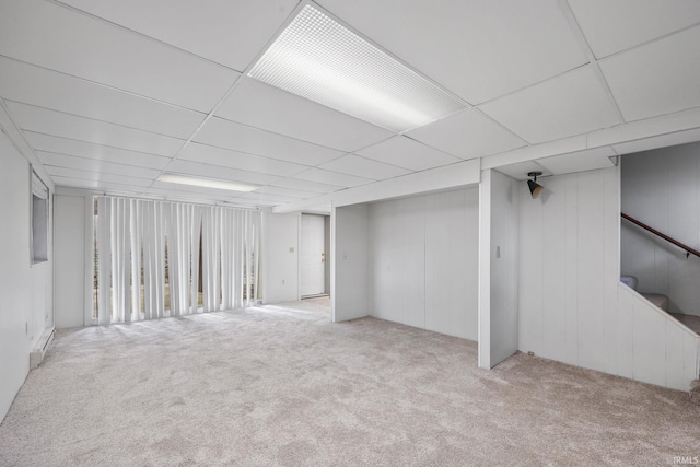 basement featuring a paneled ceiling and light colored carpet