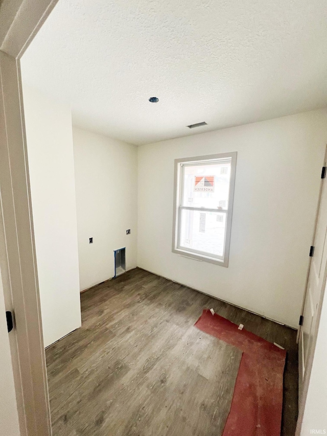 clothes washing area featuring hardwood / wood-style flooring and a textured ceiling