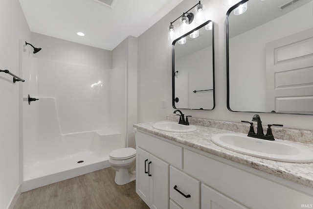 bathroom with hardwood / wood-style flooring, toilet, vanity, and walk in shower