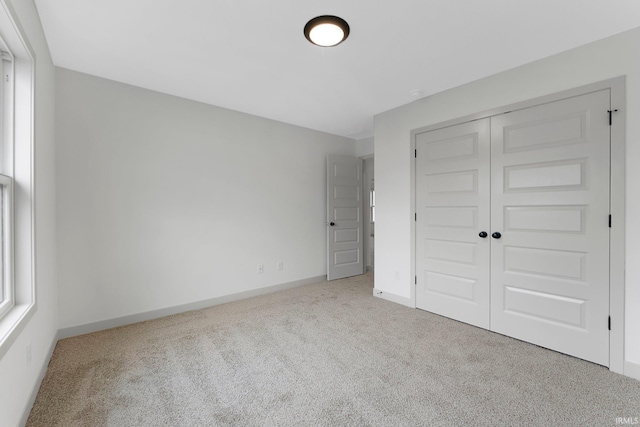 unfurnished bedroom with light colored carpet and a closet