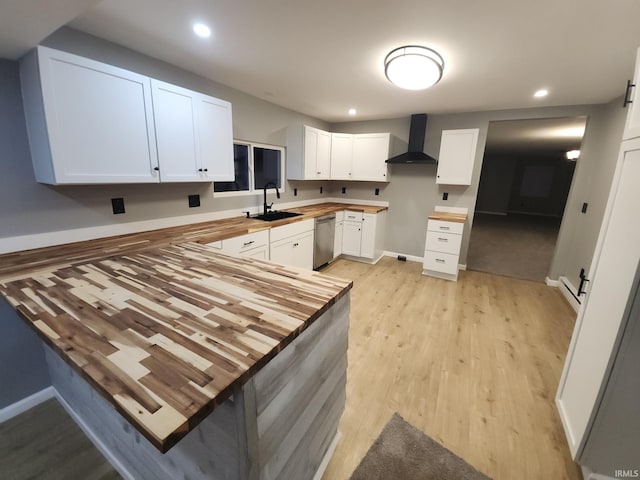 kitchen with wooden counters, white cabinets, kitchen peninsula, and wall chimney range hood