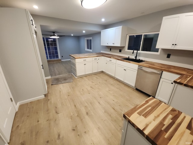 kitchen featuring white cabinetry, sink, wood counters, stainless steel dishwasher, and kitchen peninsula