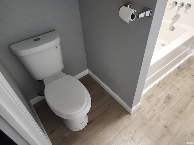 bathroom featuring hardwood / wood-style floors, toilet, and a bath