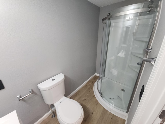 bathroom with hardwood / wood-style floors, toilet, and a shower with shower door