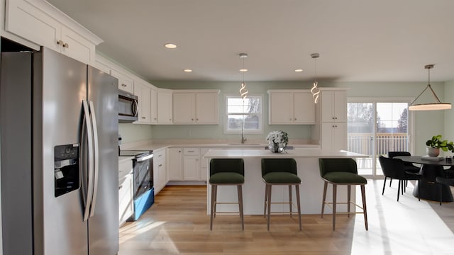 kitchen with white cabinets, appliances with stainless steel finishes, a kitchen island, and pendant lighting