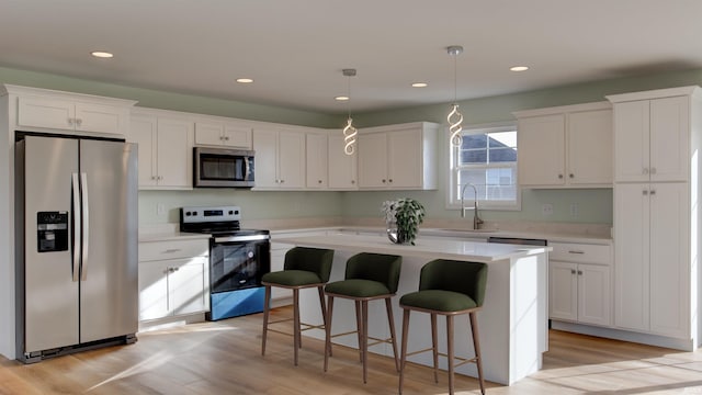 kitchen featuring appliances with stainless steel finishes, a kitchen island, pendant lighting, light hardwood / wood-style flooring, and white cabinetry