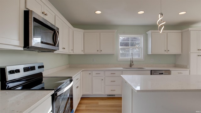 kitchen featuring white cabinets, hanging light fixtures, sink, and appliances with stainless steel finishes