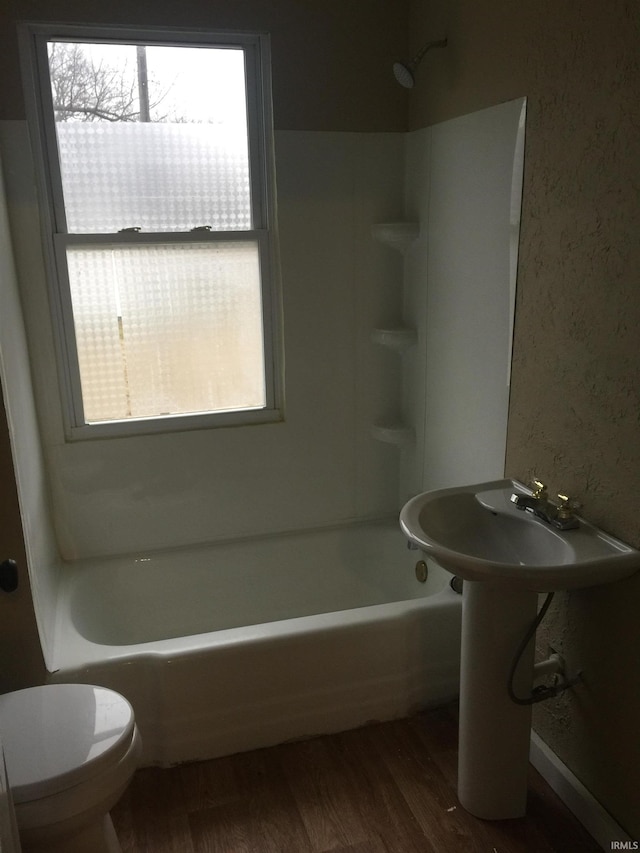 bathroom featuring wood-type flooring,  shower combination, and toilet