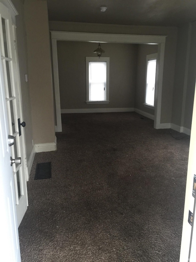 empty room with a healthy amount of sunlight and dark carpet