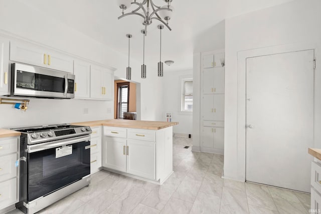 kitchen featuring wood counters, pendant lighting, stainless steel appliances, and white cabinetry