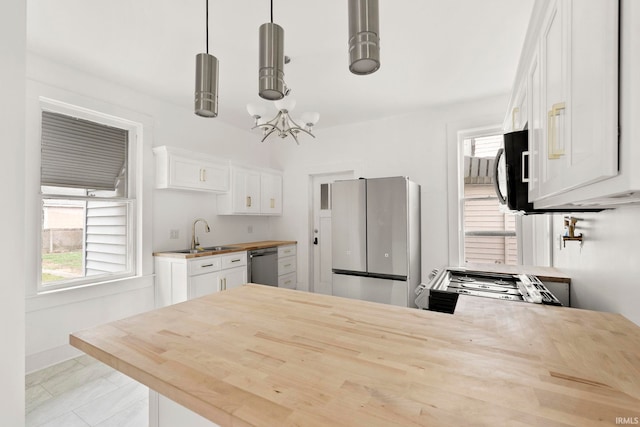 kitchen with white cabinets, decorative light fixtures, kitchen peninsula, and stainless steel appliances