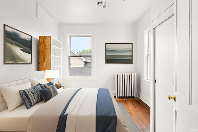 bedroom with radiator and hardwood / wood-style flooring