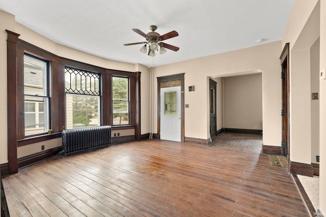 spare room featuring dark hardwood / wood-style flooring, radiator, and ceiling fan