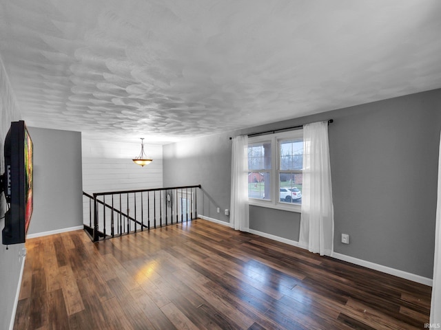 spare room featuring a textured ceiling and dark wood-type flooring